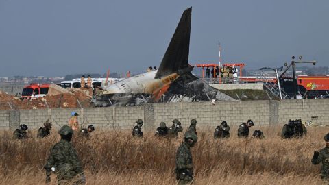 Soldados surcoreanos buscan a pasajeros desaparecidos cerca de los restos de un Boeing 737-800 de Jeju Air después de que el avión se estrellara y estallara en llamas en el Aeropuerto Internacional de Muan, en la provincia de Jeolla del Sur.