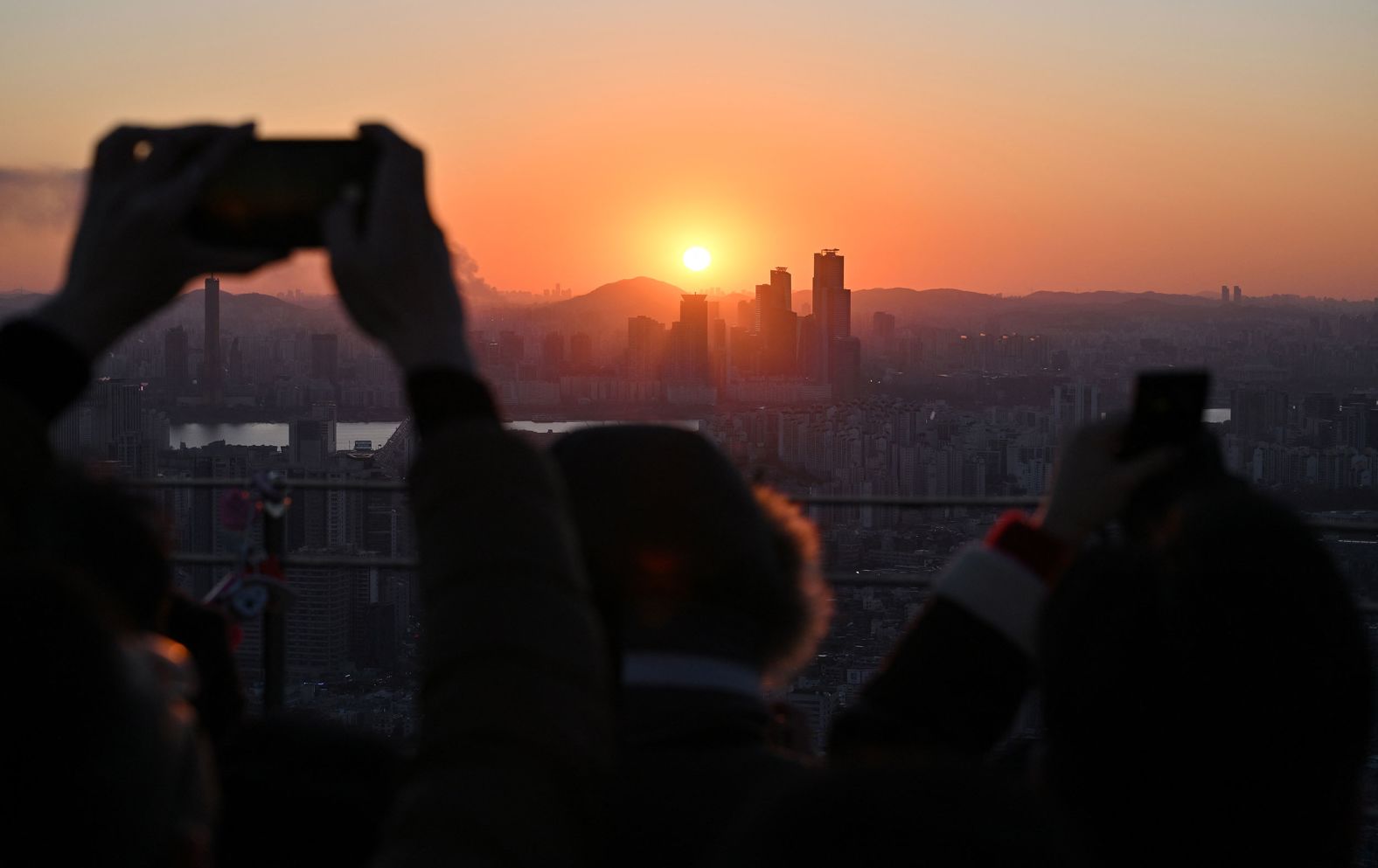 People in Seoul, South Korea, take pictures as they observe the last sunset of the year.