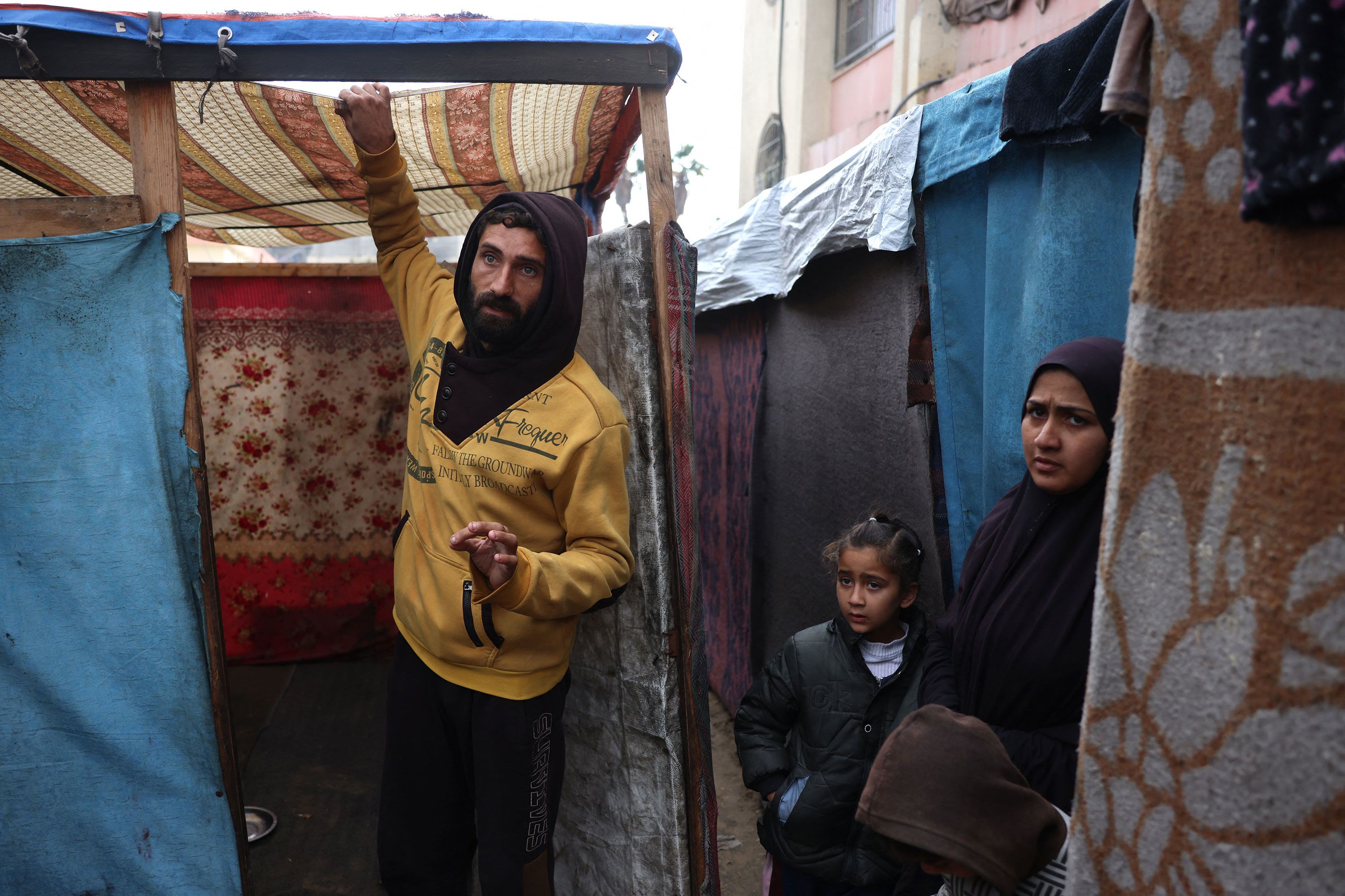 فلسطينيون يتفقدون تجمع مياه على سطح مأوى لهم في مخيم مؤقت في خان يونس، غزة