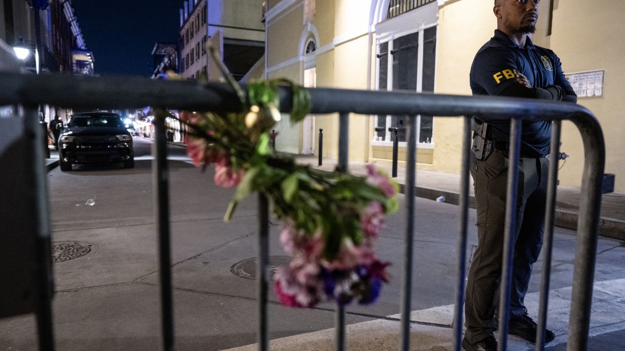 A member of the FBI looks on near a bouquet of flowers tied to a fence, a block from Bourbon Street, after at least 15 people were killed during an attack early in the morning on January 1, 2025 in New Orleans, Louisiana. A US army veteran with an Islamic State flag and "hellbent" on carnage steered a pickup truck into a crowd of New Year revelers in New Orleans on January 1, killing at least 15 people and wounding dozens, officials said. The FBI identified the attacker as Shamsud-Din Jabbar, a 42-year-old US citizen from Texas. (Photo by ANDREW CABALLERO-REYNOLDS / AFP) (Photo by ANDREW CABALLERO-REYNOLDS/AFP via Getty Images)