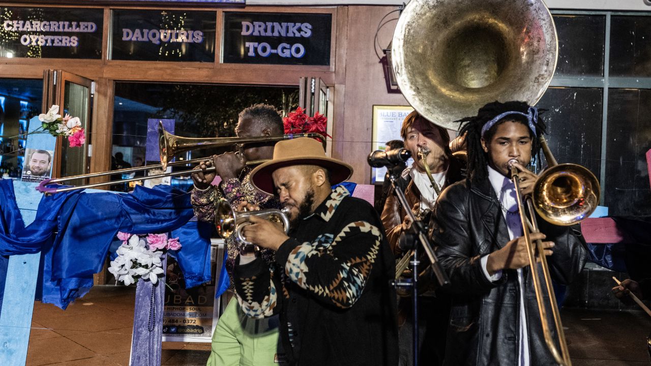 A band plays next to crosses with pictures of victims at a memorial on Bourbon Street after it reopened to the public on January 2, 2025, in New Orleans, Louisiana, following an attack on January 1 which left 14 dead. A US army veteran loyal to the Islamic State jihadist group likely acted alone when he killed 14 and injured dozens in a truck attack on a crowd of New Year revelers in New Orleans, the FBI said on January 2. (Photo by ANDREW CABALLERO-REYNOLDS / AFP) (Photo by ANDREW CABALLERO-REYNOLDS/AFP via Getty Images)