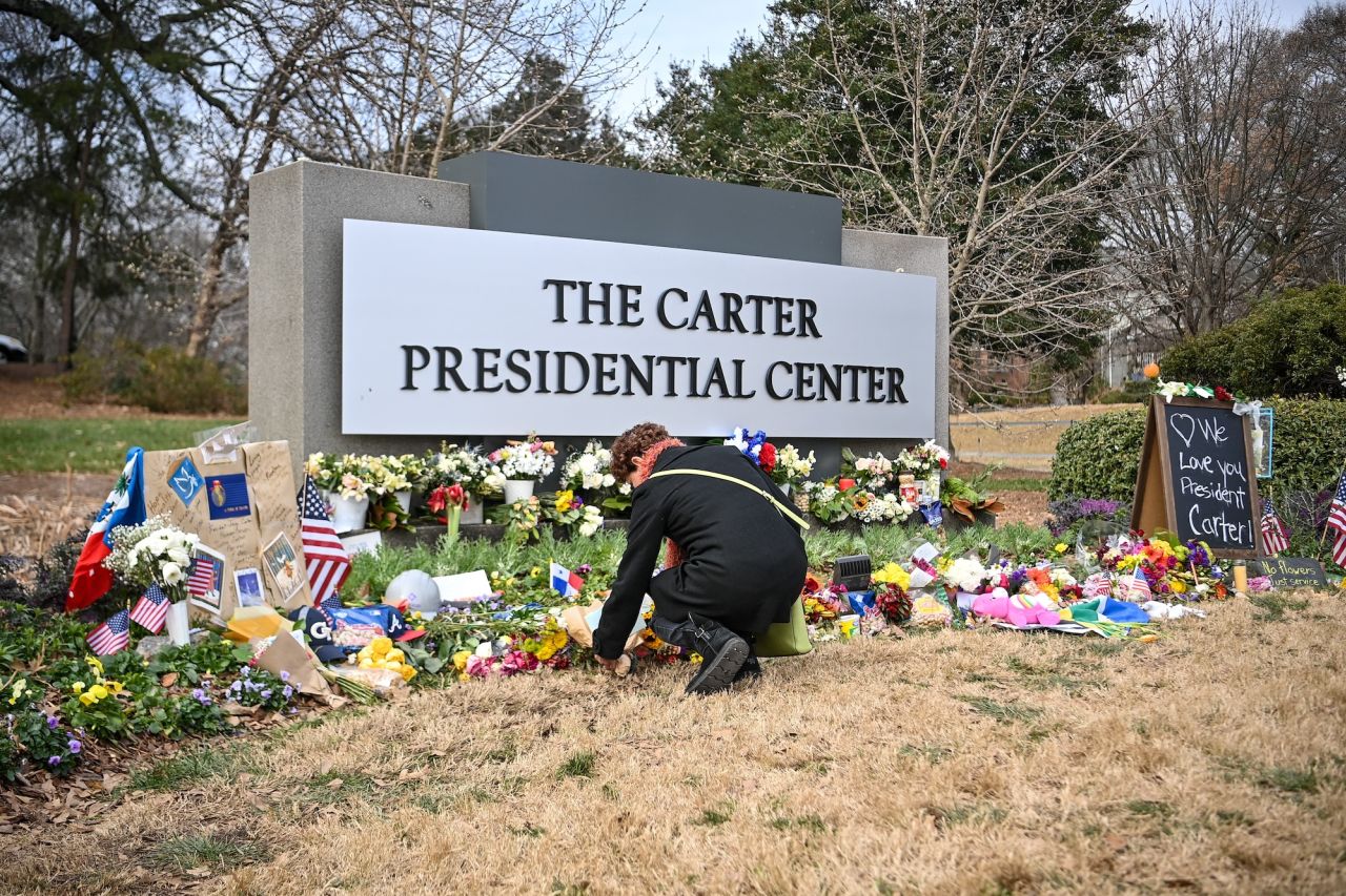 A person lays flowers at a memorial for former President Jimmy Carter in front of the Carter Presidential Center in Atlanta on Sunday.