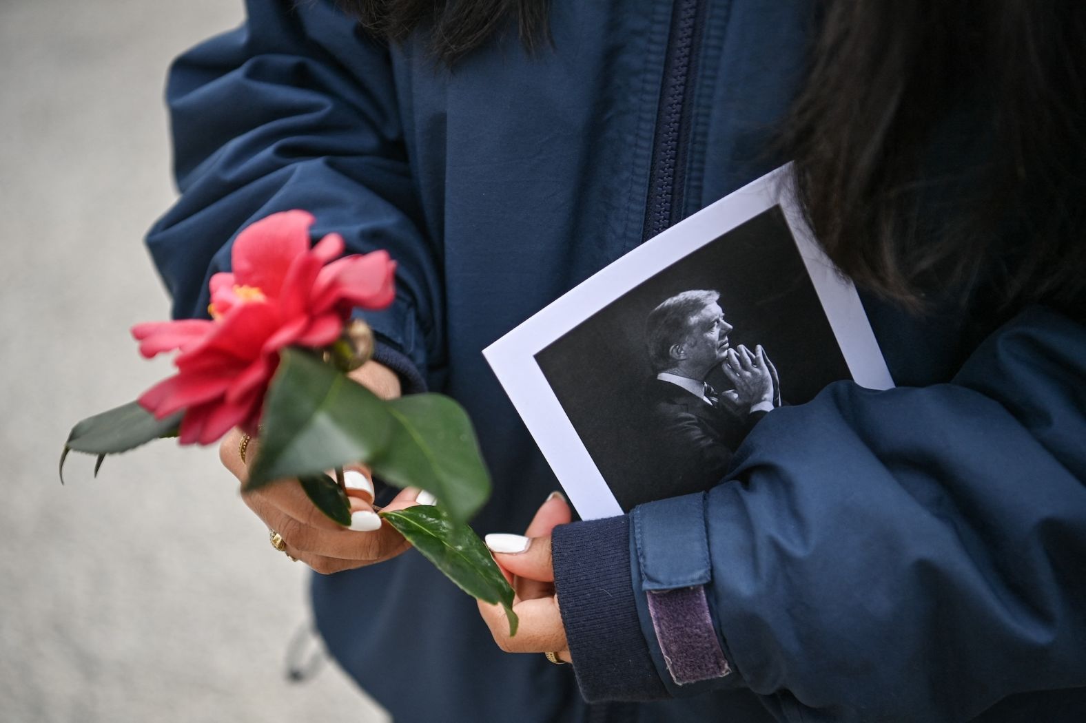 A woman holds a flower and a picture of Carter at a memorial in front of the Carter Center in Atlanta on January 5.