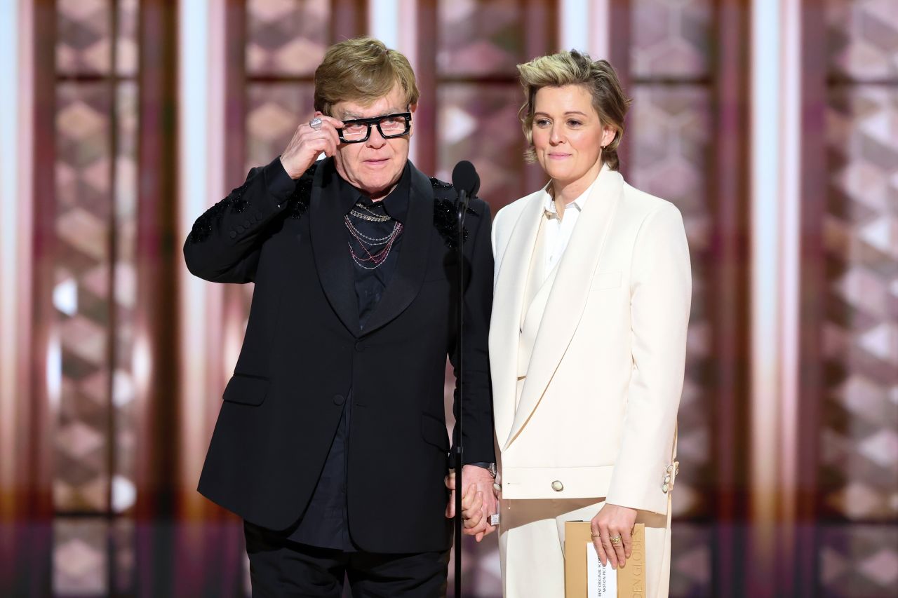 Elton John and Brandi Carlile speak on stage at the Golden Globes.