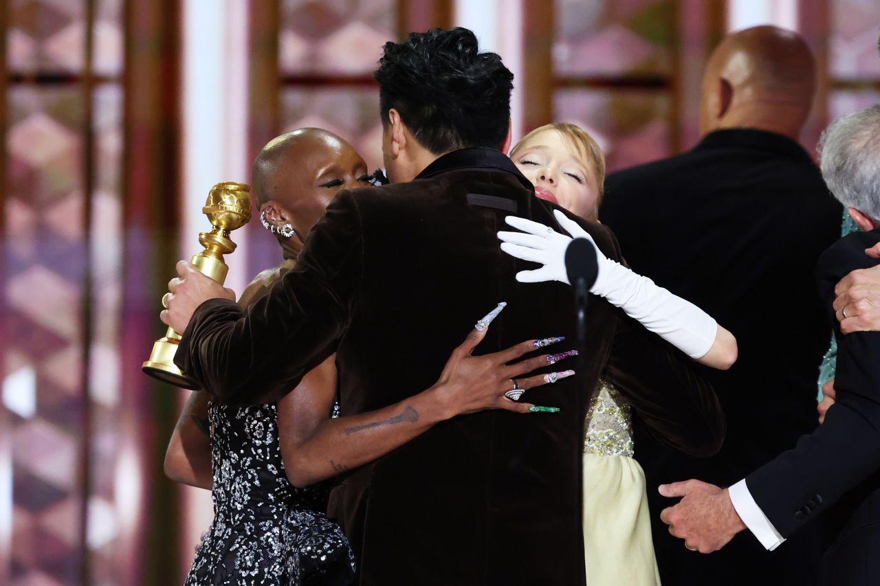 Cynthia Erivo, Jon M. Chu and Ariana Grande embrace on stage at the Golden Globe Awards on Sunday, January 5.