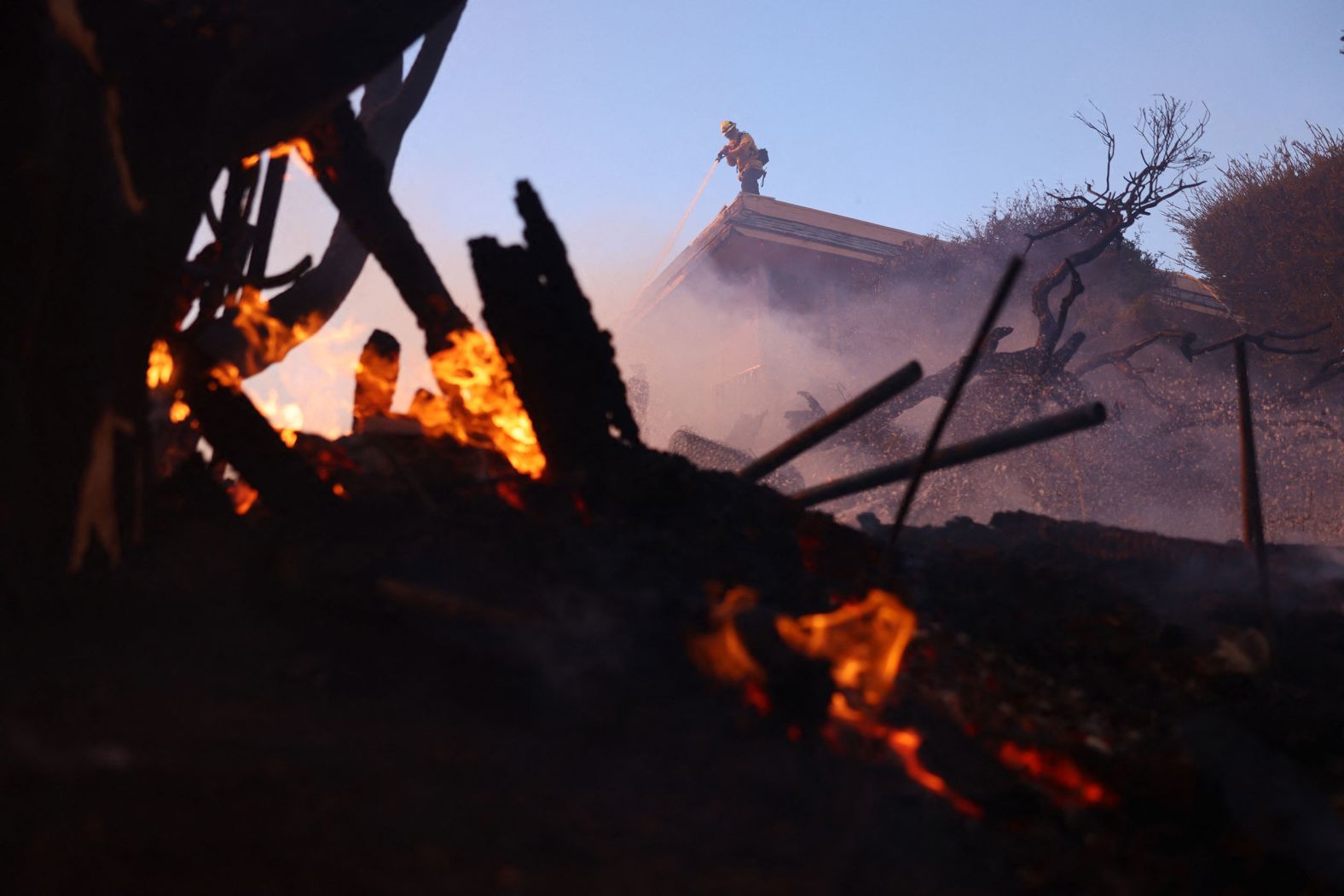 A firefighter douses a hot spot in Pacific Palisades.