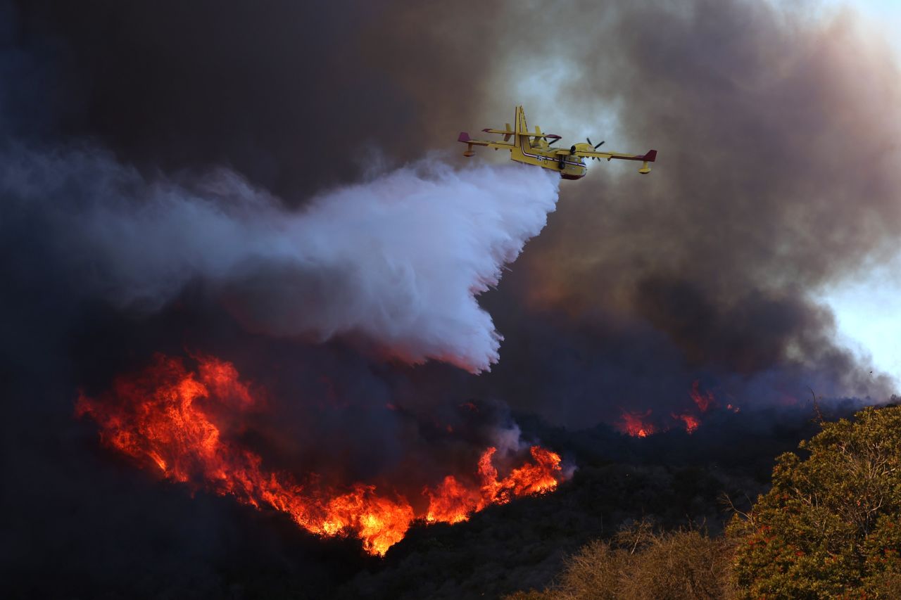 A plane drops water on the Palisades Fire in Pacific Palisades on Tuesday.