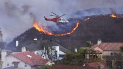 Un helicóptero sobrevuela las casas amenazadas por el incendio de Palisades en Pacific Palisades, California, 7 de enero de 2025. Un rápido incendio forestal en un suburbio de Los Ángeles quemó edificios y provocó evacuaciones el martes debido a los vientos que azotaron la región. Más de 80 hectáreas ardían en Pacific Palisades, una zona de lujo con casas de varios millones de dólares en las montañas de Santa Mónica, cerrando una autopista clave y cubriendo la zona con un humo espeso.