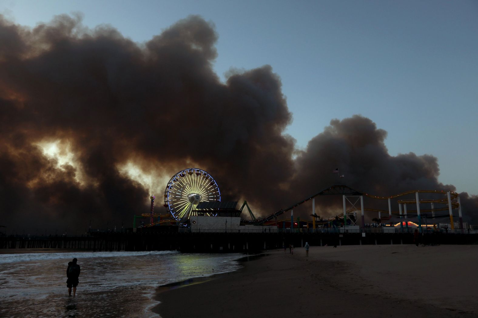 The Palisades Fire burns several miles behind the Santa Monica Pier.