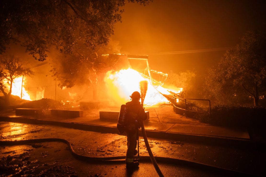 Un bombero lucha contra las llamas del incendio Palisades que quema el Theatre Palisades durante una fuerte tormenta de viento el 8 de enero de 2025 en el barrio Pacific Palisades de Los Ángeles, California. El rápido incendio forestal está amenazando las casas del barrio costero en medio de los intensos vientos de Santa Ana y las condiciones secas en el sur de California.