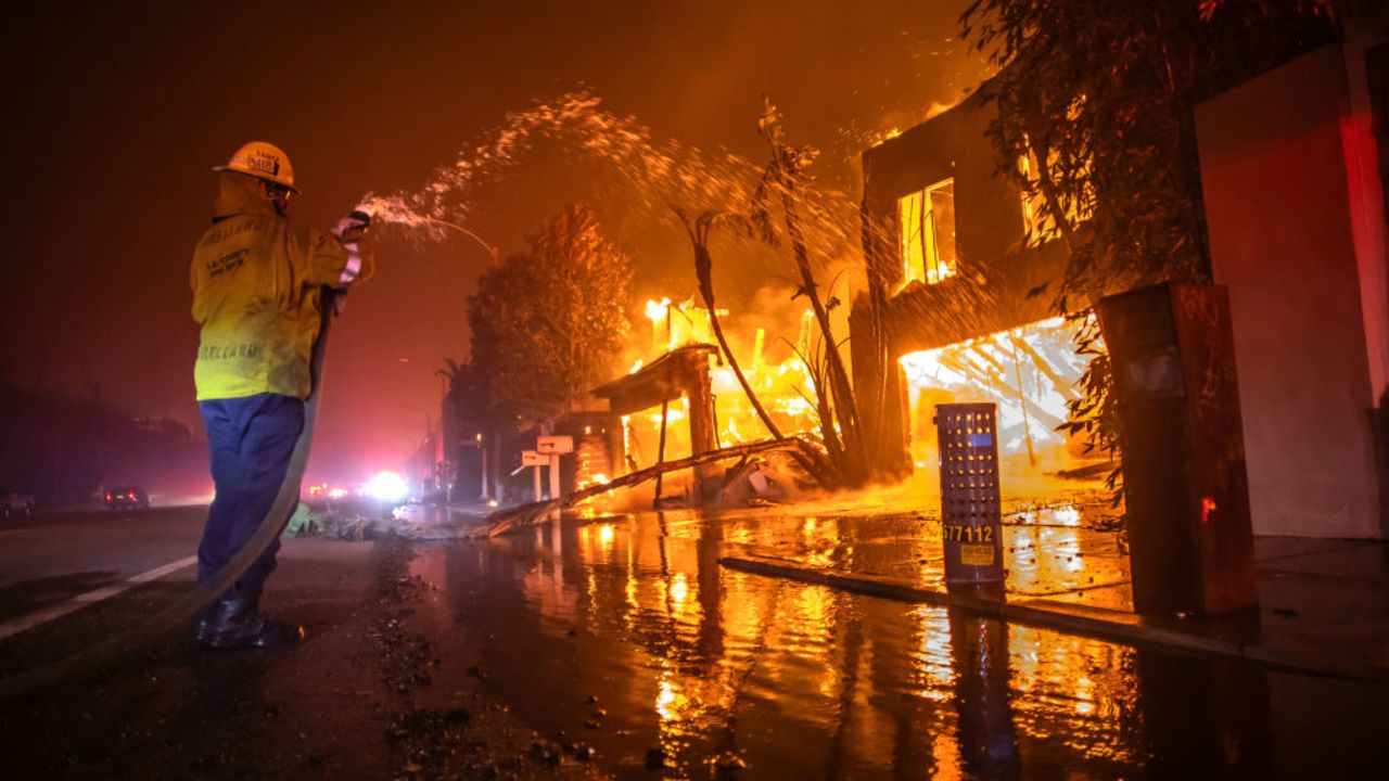 LOS ANGELES, CALIFORNIA - JANUARY 8: A firefighter battles the Palisades Fire while it burns homes at Pacific Coast Highway amid a powerful windstorm on January 8, 2025 in Los Angeles, California. The fast-moving wildfire has grown to more than 2900-acres and is threatening homes in the coastal neighborhood amid intense Santa Ana Winds and dry conditions in Southern California. (Photo by Apu Gomes/Getty Images)