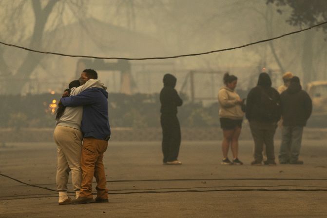 ALTADENA, CALIFORNIA - JANUARY 8: People hug in a neighborhood where a large portion of the homes burned in the Eaton Fire on January 8, 2025 in Altadena, California. Powerful Santa Ana winds pushed the fire across more than 10,000 acres in less than 24 hours, destroying potentially hundreds of homes and killing five people so far. At least 1,000 structures have burned and 70,000 people are forced from their homes in the Los Angeles area as multiple dangerous wildfires continue to erupt. (Photo by David McNew/Getty Images)