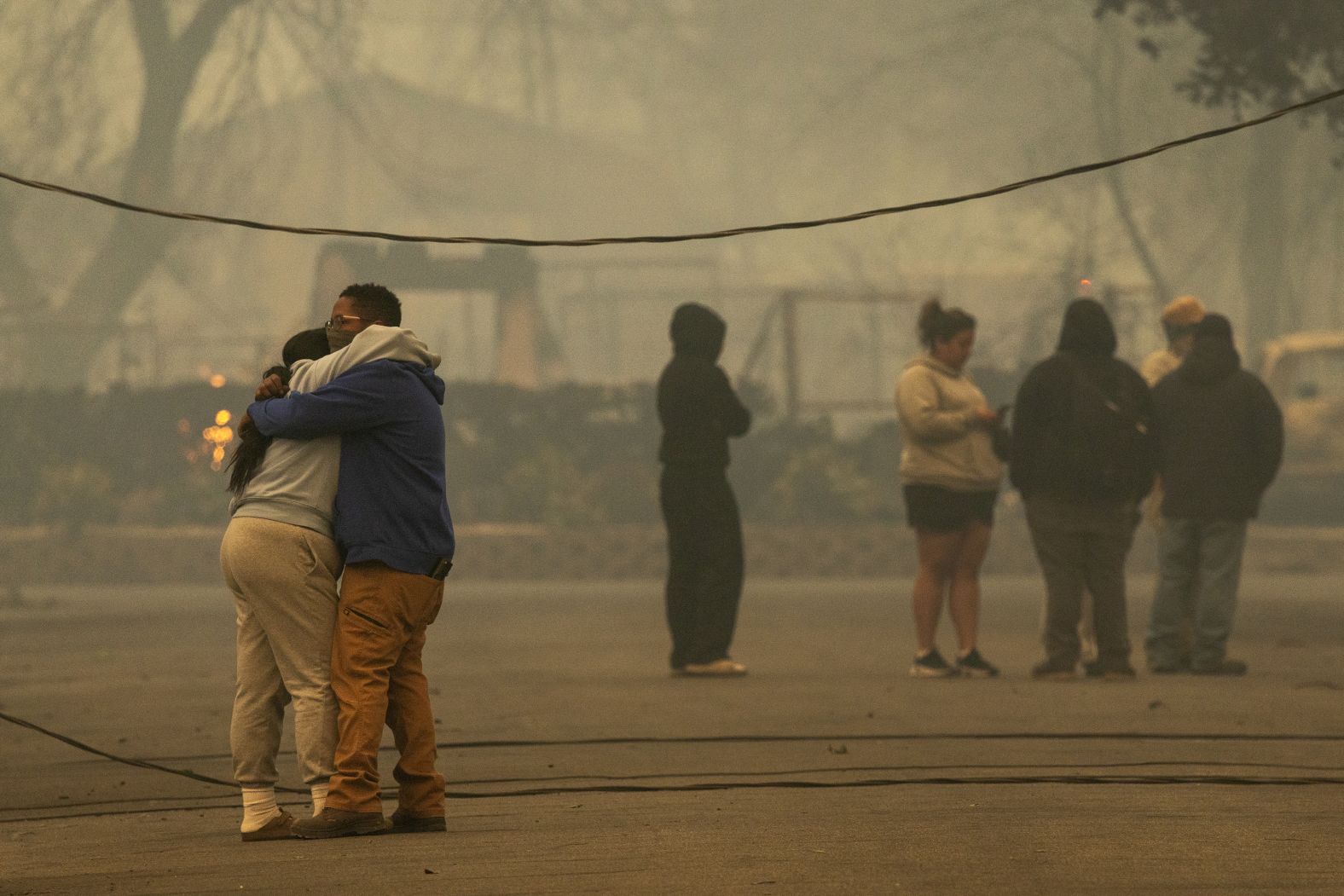 ALTADENA, CALIFORNIA - JANUARY 8: People hug in a neighborhood where a large portion of the homes burned in the Eaton Fire on January 8, 2025 in Altadena, California. Powerful Santa Ana winds pushed the fire across more than 10,000 acres in less than 24 hours, destroying potentially hundreds of homes and killing five people so far. At least 1,000 structures have burned and 70,000 people are forced from their homes in the Los Angeles area as multiple dangerous wildfires continue to erupt. (Photo by David McNew/Getty Images)