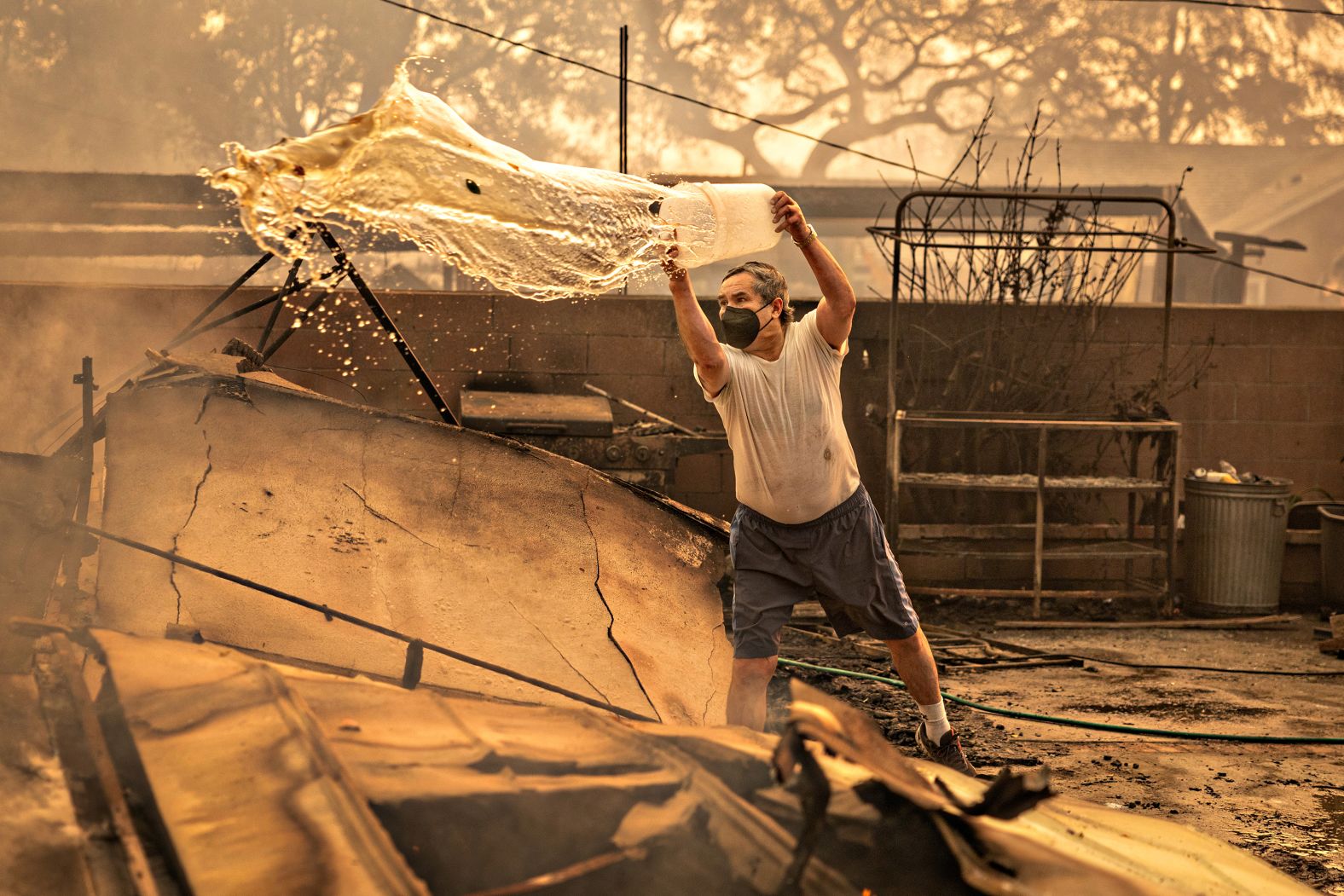 Altadena, CA - January 08: Juan Munoz pours water on the fire ravaged remains of his home where he has lived for over thirty nine years during the Eaton fire on Wednesday, Jan. 8, 2025 in Altadena, CA. (Jason Armond / Los Angeles Times via Getty Images)