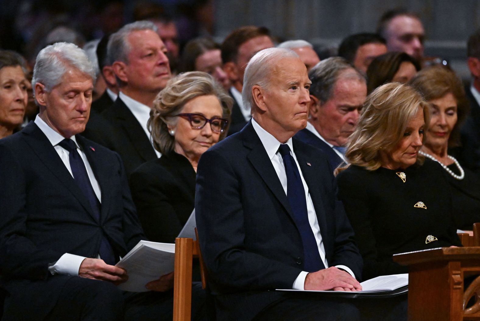 The Bidens sit in front of the Clintons and the Bushes during the funeral.