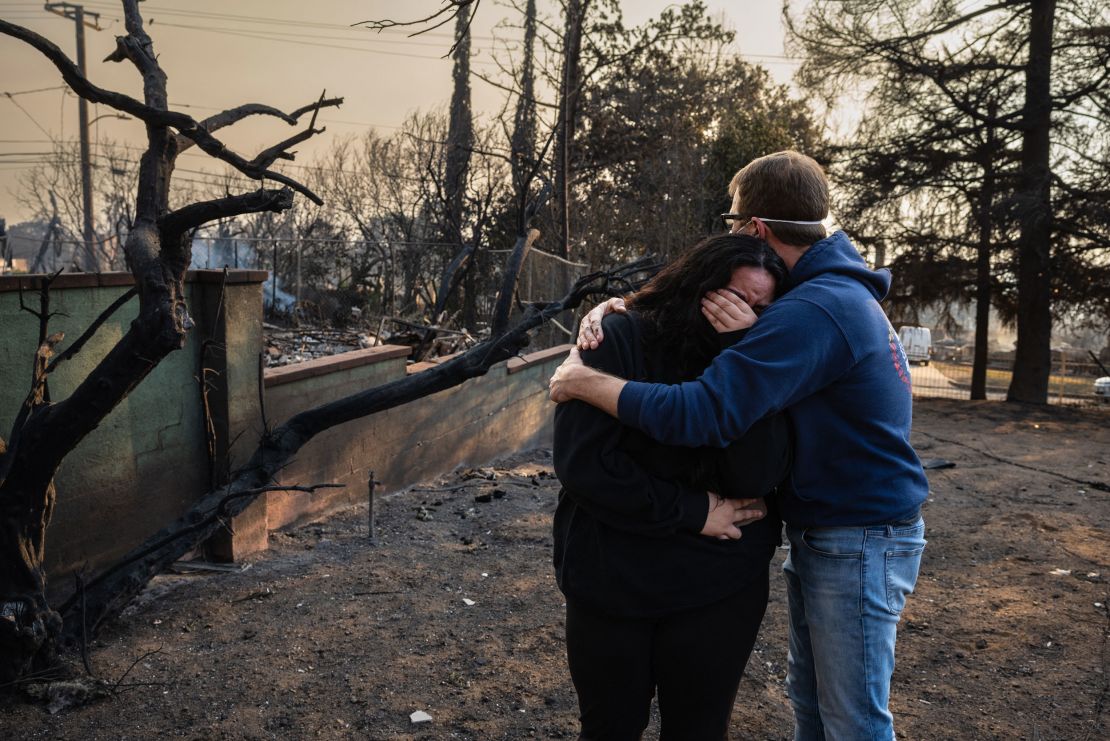 A man comforts his daughter by the charred ruins of their family home which burned down in the Eaton Fire in Altadena, California.