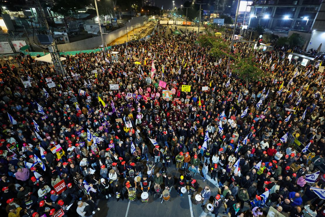 Demonstrators lift placards and national flags during an anti-government protest in Tel Aviv, Israel, on January 11. The demonstrators were calling for action to secure the release of Israelis held hostage since October 2023.