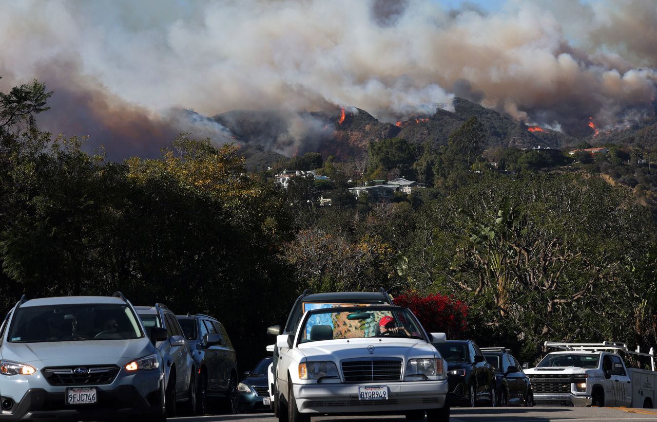 People drive out of harm’s way as the Palisades Fire burns on January 7 in Pacific Palisades, California.