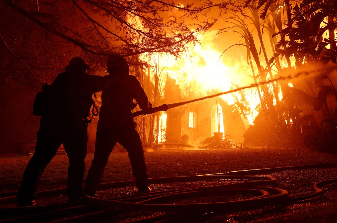 Bomberos del condado de Los Ángeles rocían agua sobre una casa en llamas mientras el incendio Eaton avanza por la zona el 8 de enero de 2025 en Altadena, California.