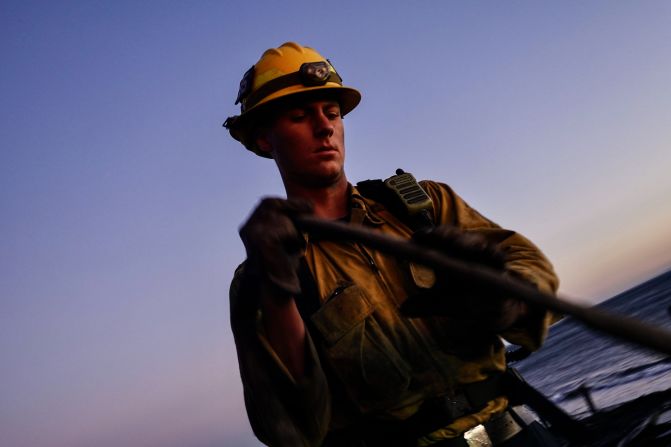 A firefighter works to extinguish lingering fires in Malibu.