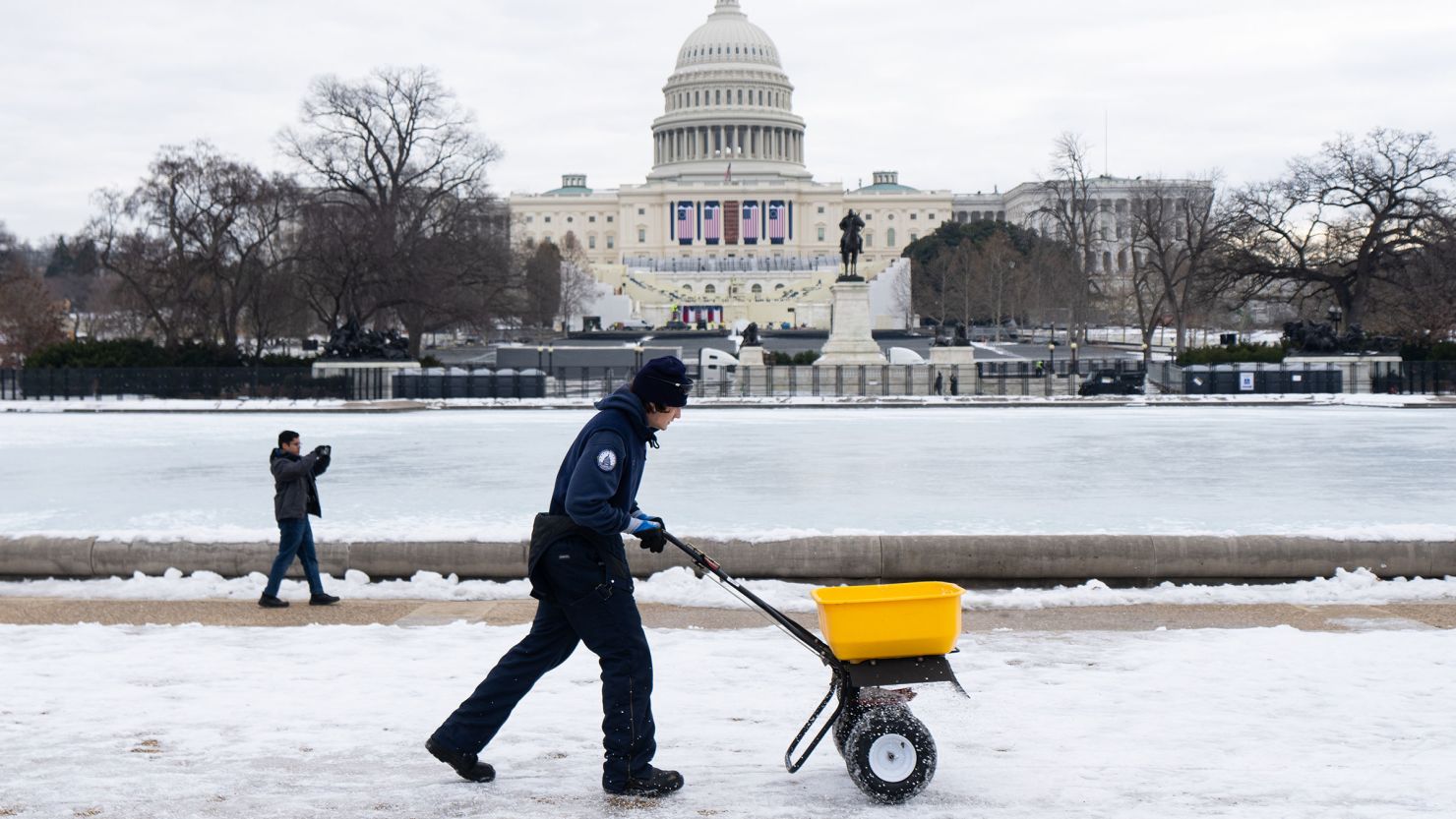 An Architect of the Capitol worker spreads de-icer around the Capitol Reflecting Pool on Monday, in advance of next week's Inauguration ceremony.