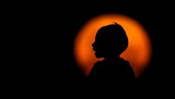 The silhouette of a boy is seen against a full moon rising over the Rio de la Plata in Buenos Aires on January 13, 2025. (Photo by LUIS ROBAYO / AFP) (Photo by LUIS ROBAYO/AFP via Getty Images)