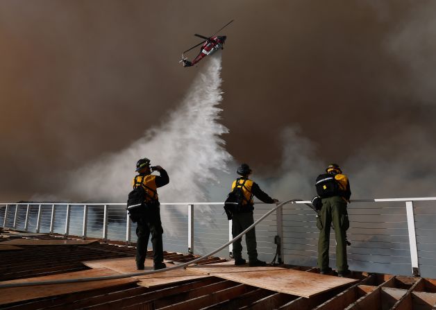 Firefighters watch as water is dropped on the Palisades Fire.