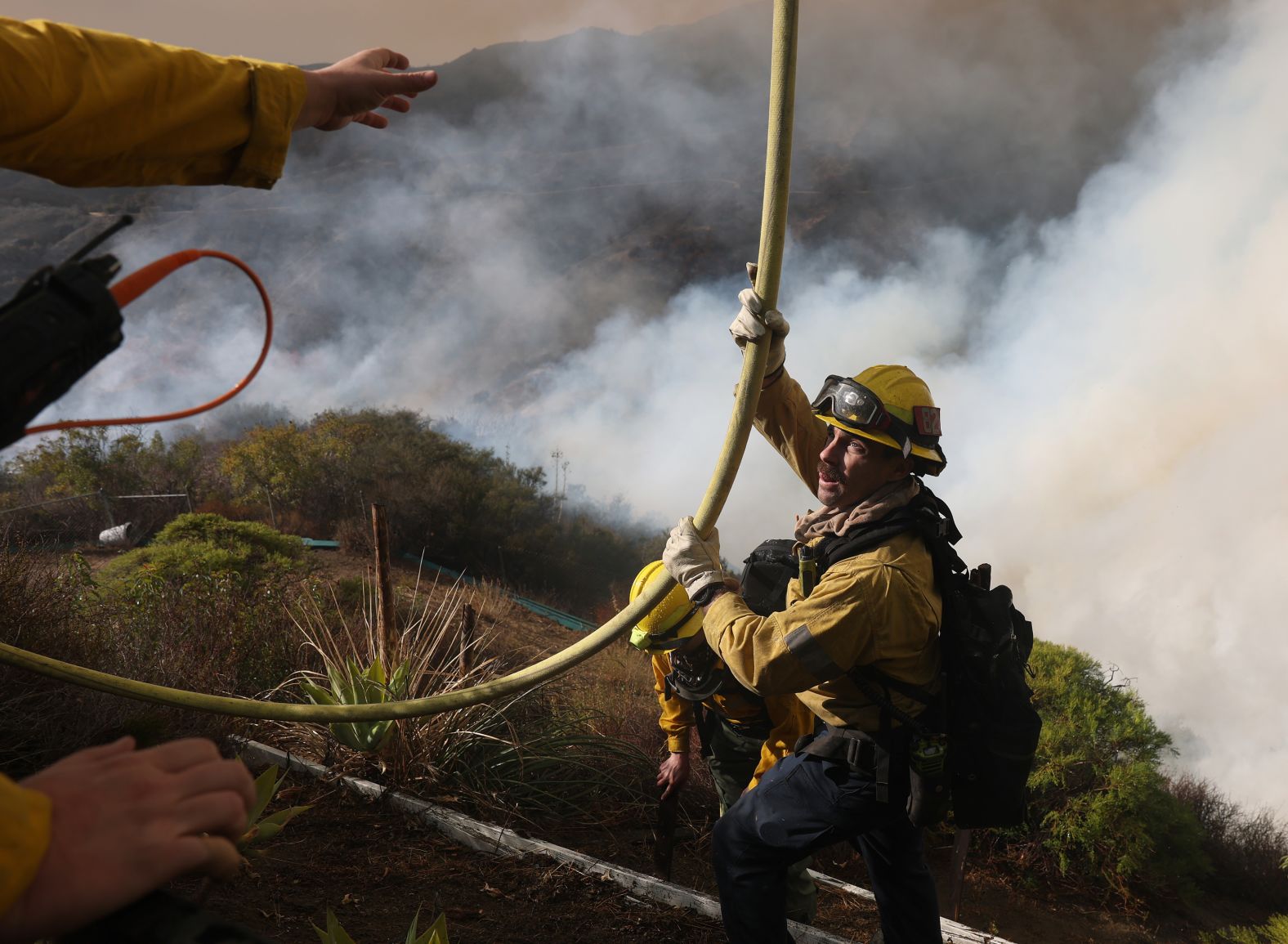 Firefighters pull a hose as they battle the Palisades Fire.