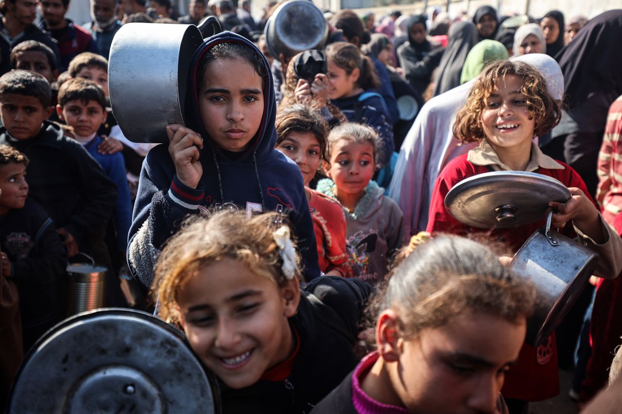 Displaced Palestinians gather to receive food cooked by a charity kitchen in Deir al-Balah, Gaza, on Thursday.