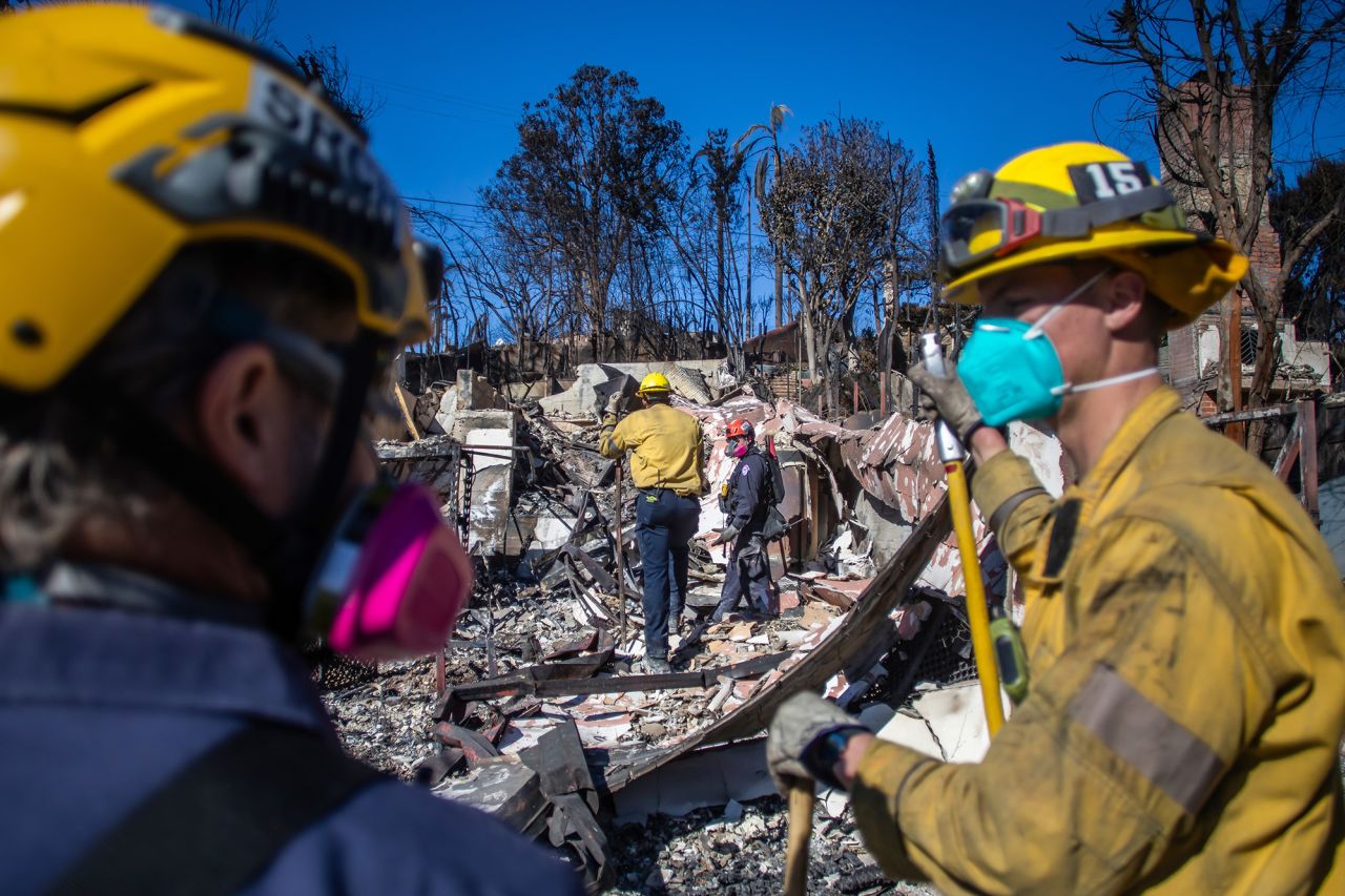 Los Angeles Fire Fighters and Sacramento Fire Fighters Urban Search & Rescue team inspect a burnt house in the Pacific Palisades neighborhood on Thursday.