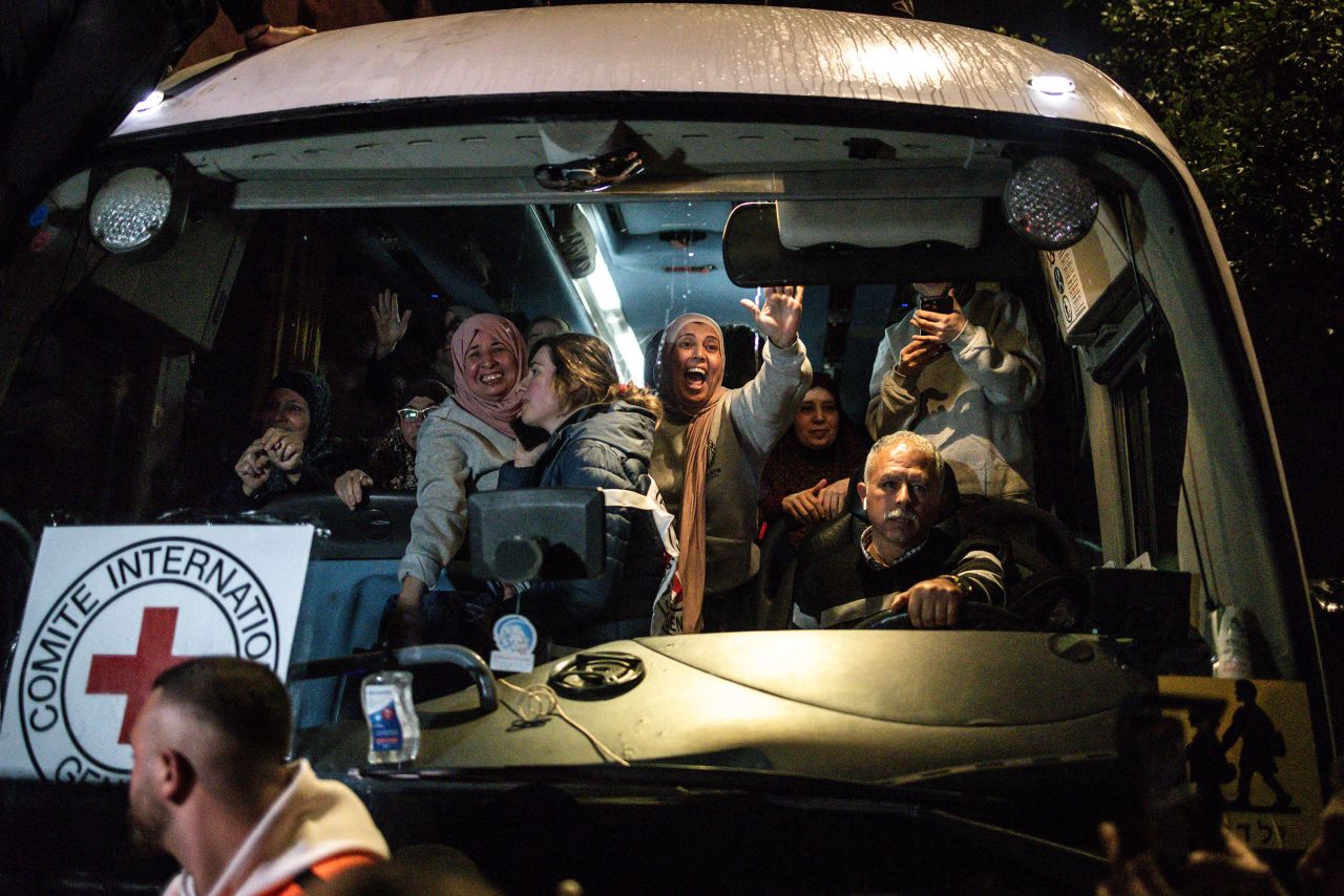 Palestinian freed prisoners wave to the crowd from a Red Cross as they arrive in Beitunia, on the outskirts of Ramallah, in the early hours of Monday.