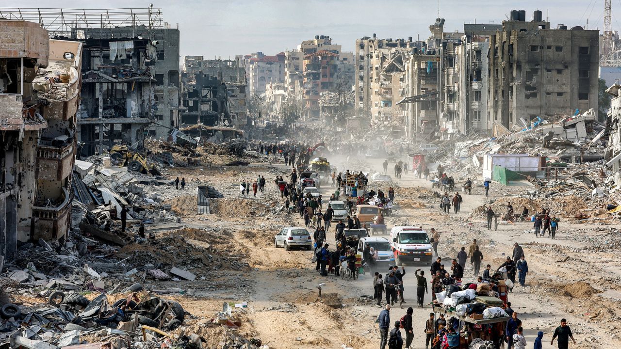 People walk past the rubble of collapsed buildings along Saftawi street in Jabalia in the northern Gaza Strip on January 20, 2025 a day after a ceasefire deal in the war between Israel and Hamas went into effect. (Photo by Omar AL-QATTAA / AFP) (Photo by OMAR AL-QATTAA/AFP via Getty Images)