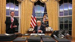 US President Donald Trump holds up outgoing President Joe Biden's letter as he signs executive orders in the Oval Office of the White House in Washington, DC, on January 20, 2025. (Photo by Jim WATSON / POOL / AFP) (Photo by JIM WATSON/POOL/AFP via Getty Images)