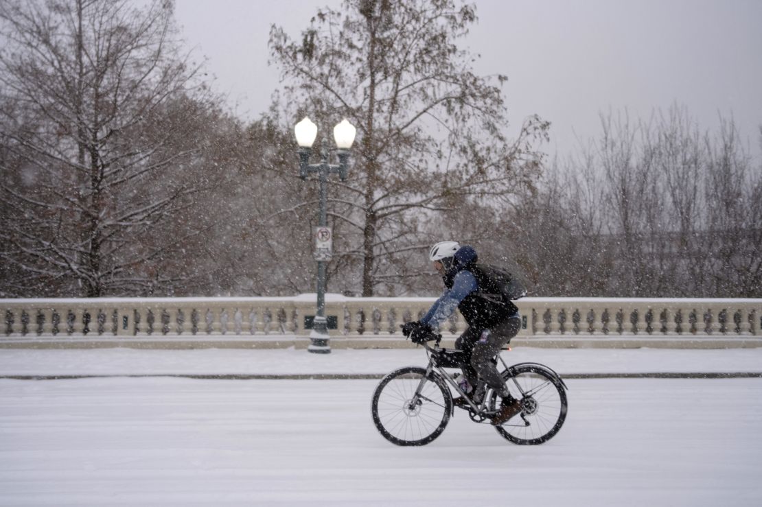 A man rides his bicycle along the Sabine Street Bridge near downtown as a winter storm brings heavy bands of snow and sleet Tuesday to Houston.