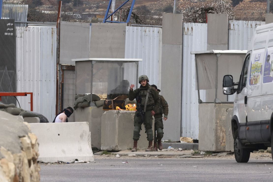 Israeli soldiers detain a Palestinian man at a checkpoint as Israeli authorities close an entrance to the occupied West Bank city of Hebron Wednesday.