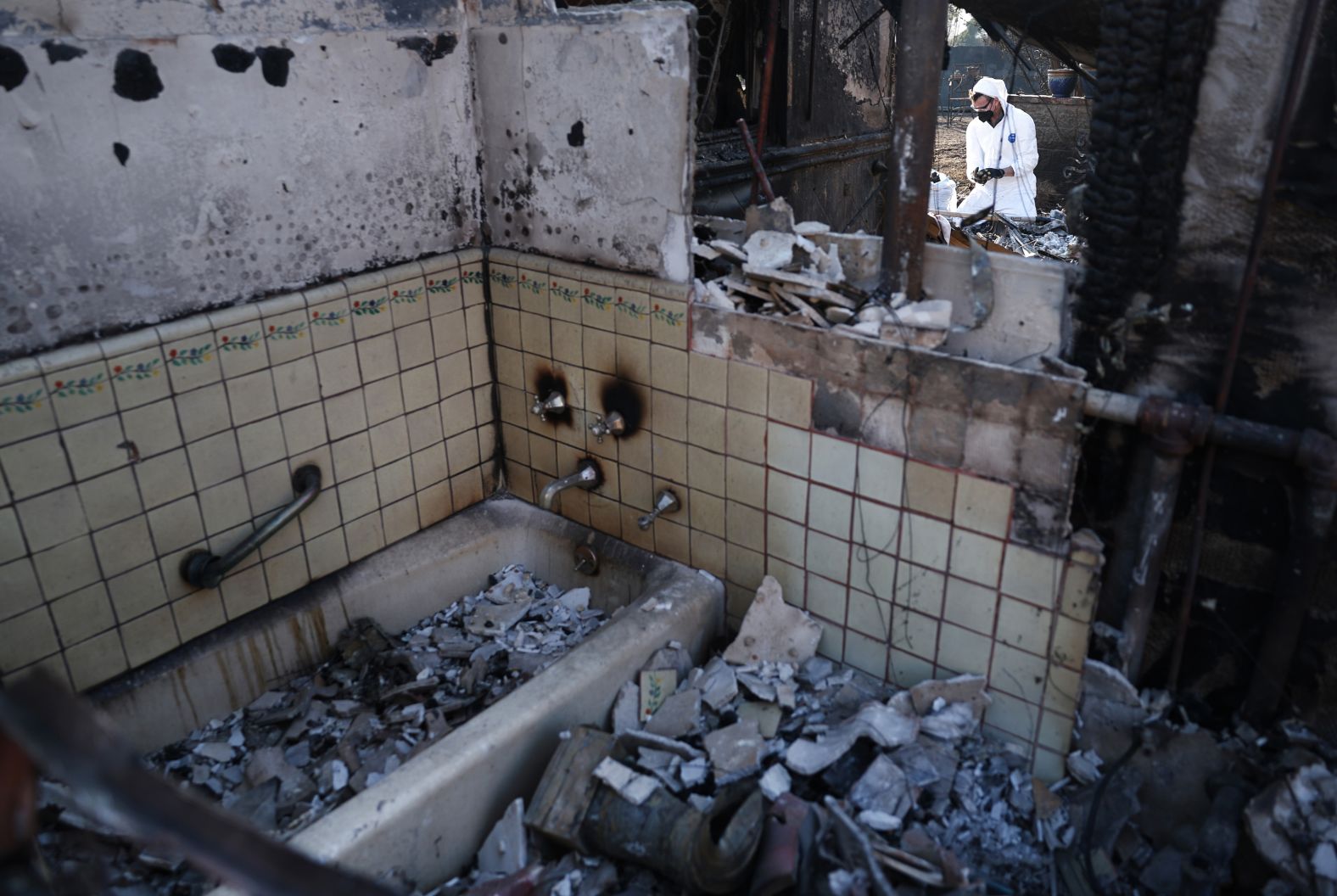 Drew Sandoval searches for items in the rubble of his friend Michele Docherty-Bond's home in Pasadena on January 18. It burned in the Eaton Fire.