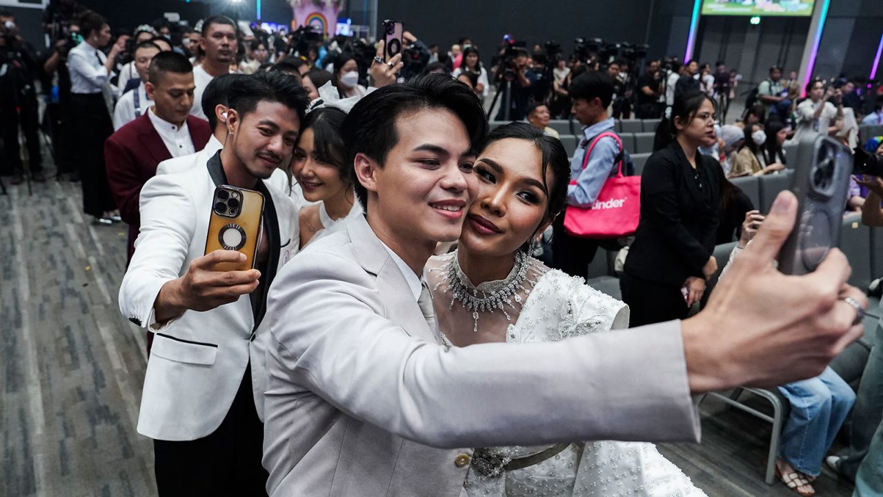 Same-sex couples take selfies of themselves at a marriage celebration at a shopping mall in Bangkok on January 23, 2025.