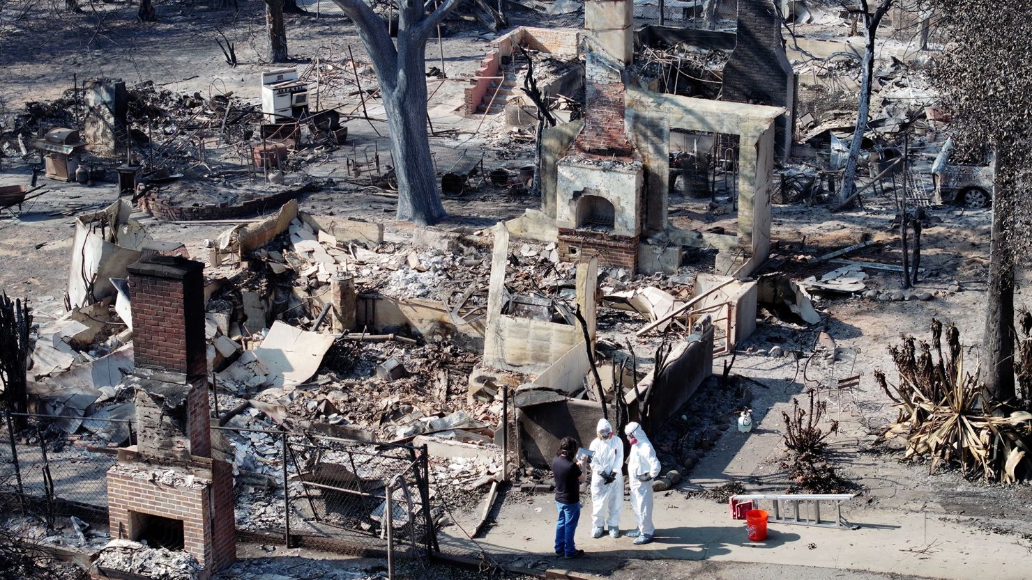 An aerial view of a couple meeting with a FEMA representative while searching through the remains of their home which burned in the Eaton Fire on January 19 in Altadena, California.