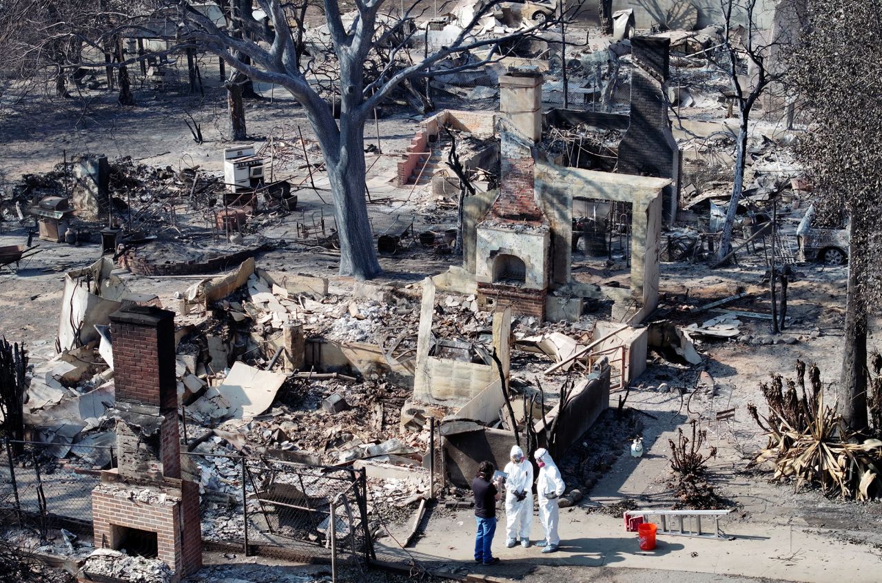 An aerial view of a couple meeting with a FEMA representative while searching through the remains of their home which burned in the Eaton Fire on January 19 in Altadena, California.