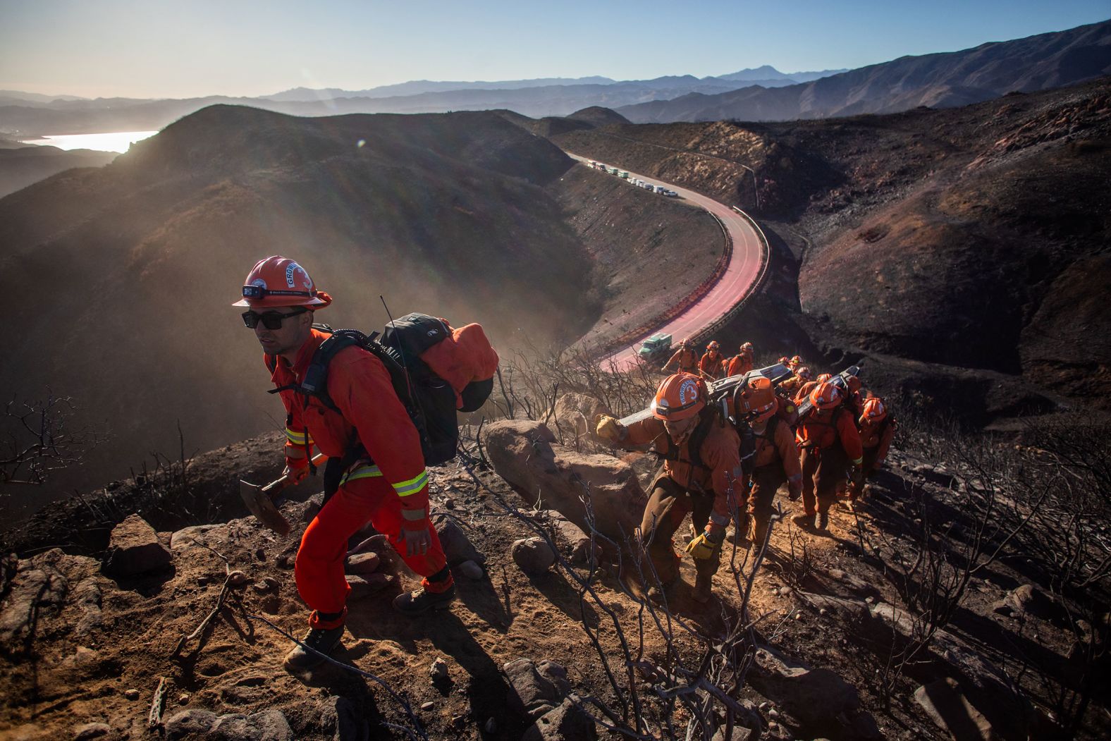 Inmate firefighters trek up a mountain to create a fire containment line as they try to help control the Hughes Fire in Castaic on Thursday, January 23.