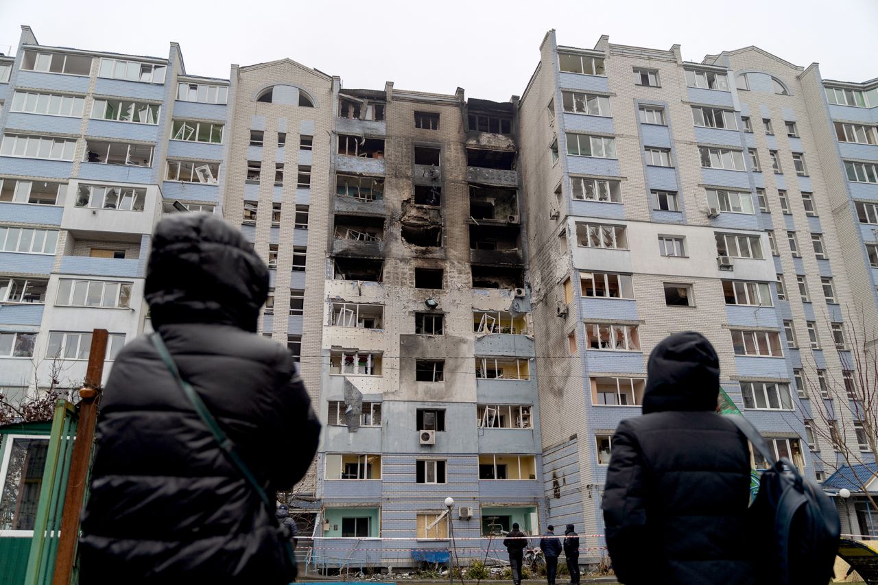 People look at a damaged residential building following Russian aerial attacks in Kyiv on January 24.