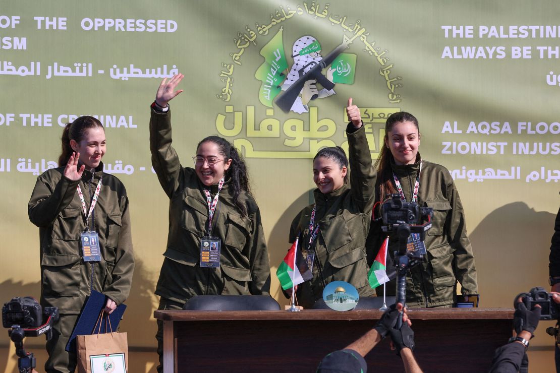 Four Israeli hostages wave on a stage before Hamas fighters hand them over to a team from the Red Cross in Gaza City on January 25, 2025.