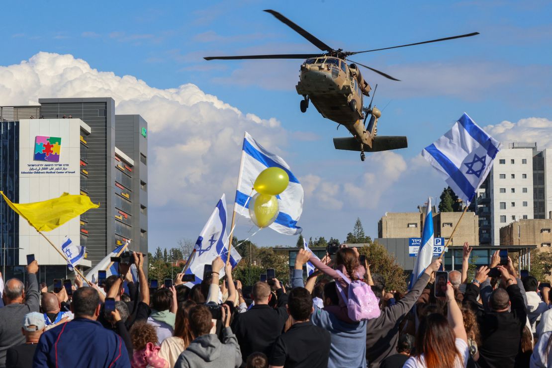 As pessoas acenam bandeiras nacionais israelenses como um helicóptero militar que transporta quatro terras israelenses recém-lançadas no Hospital Beilinson em Petah Tikva, Israel, em 25 de janeiro.