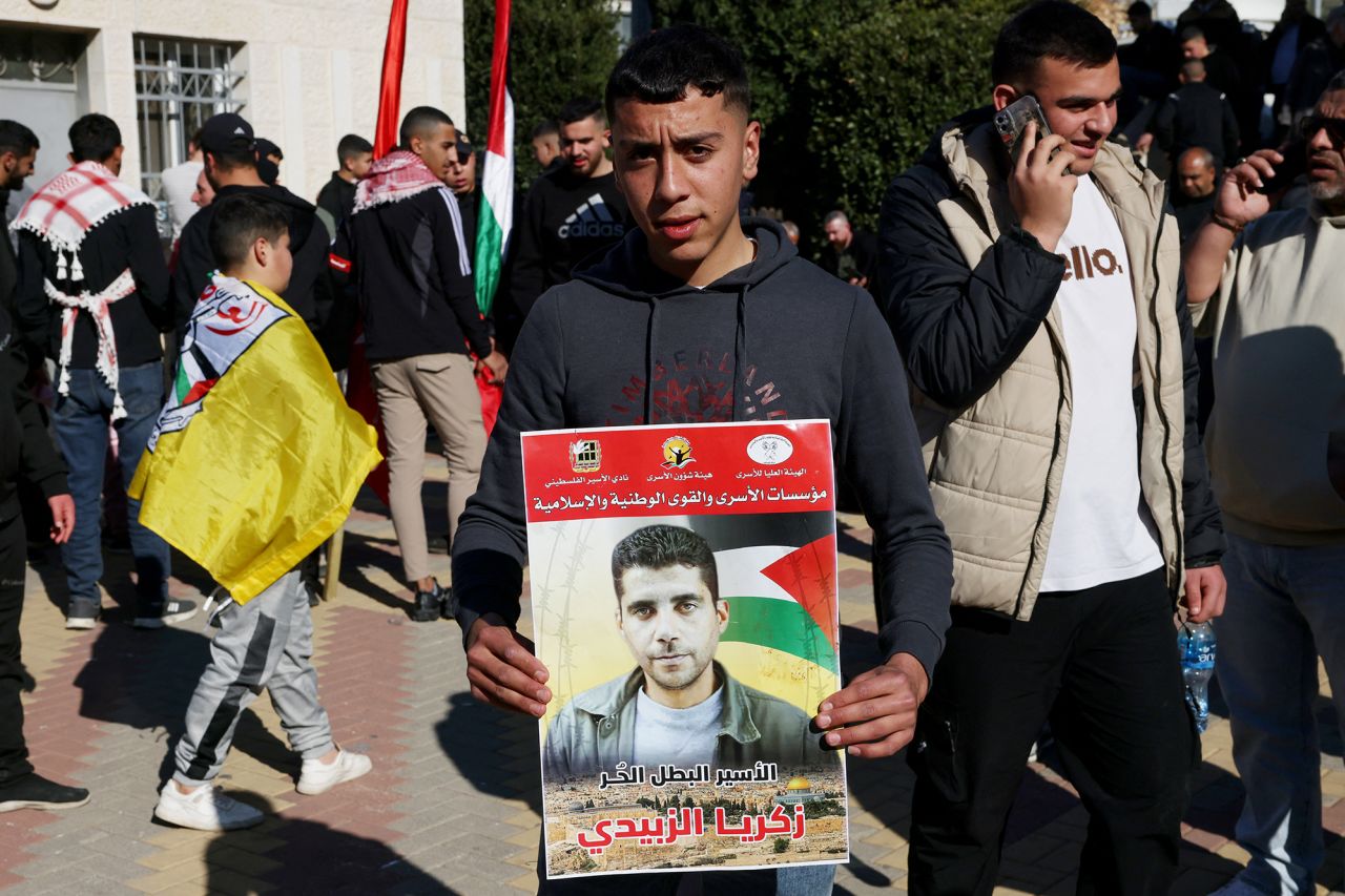 A Palestinian youth holds a portrait of Zakaria Zubeidi, a leader of Al-Aqsa Martys Brigades, as people gathered in Ramallah to receive released Palestinian prisoners on Thursday.