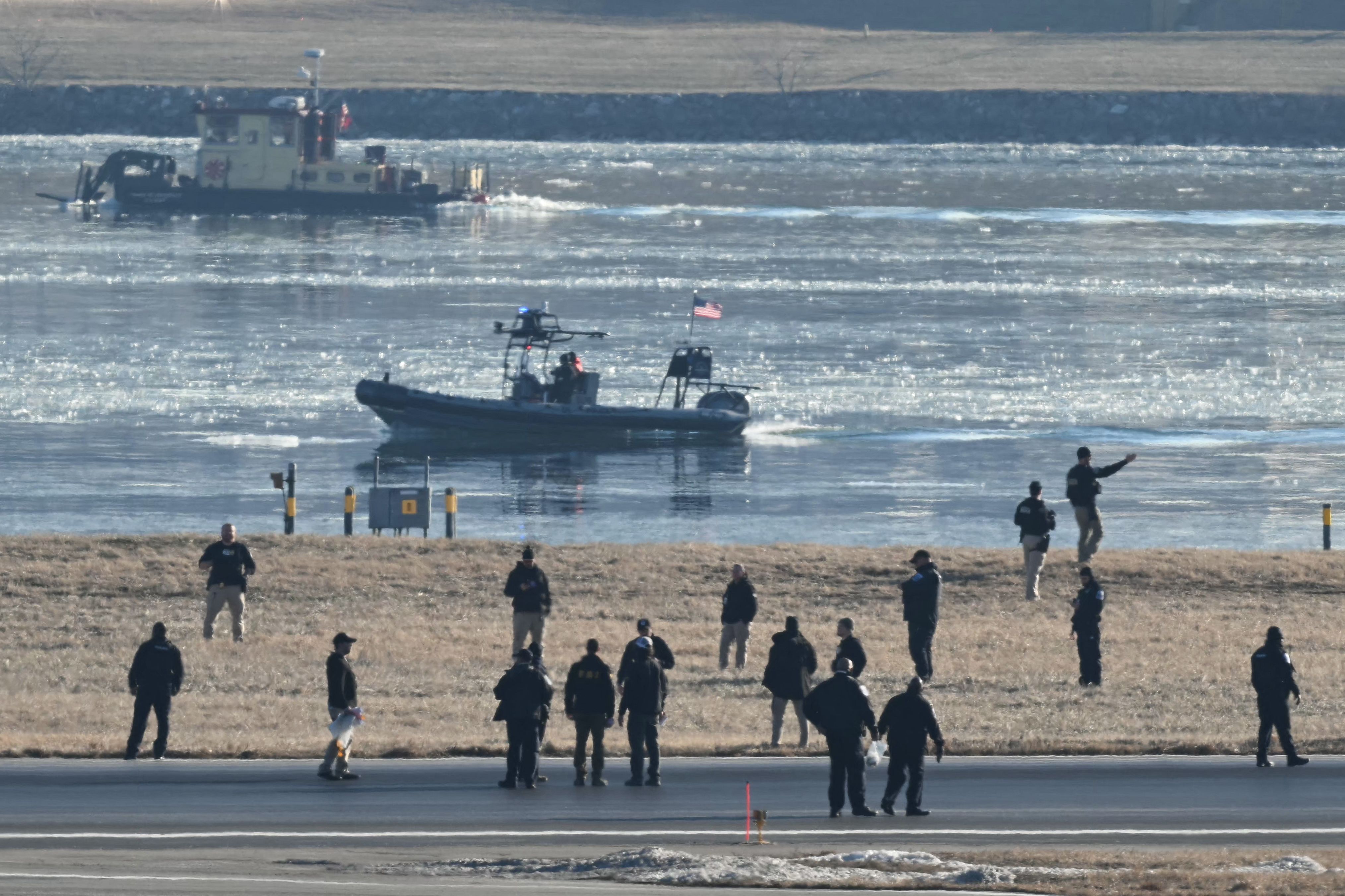 Emergency workers are seen on a runway at the airport as rescue crews search the waters of the nearby Potomac River on Thursday.