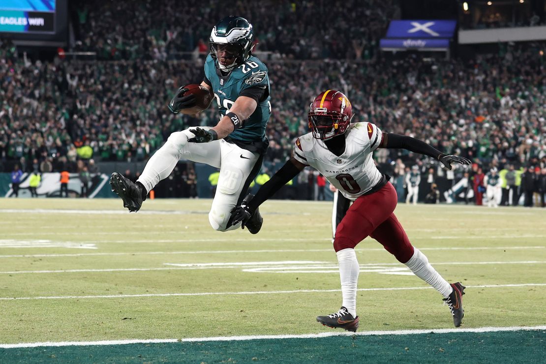 El corredor de los Philadelphia Eagles, Saquon Barkley, anota un touchdown contra Mike Sainristil de los comandantes de Washington durante el cuarto trimestre en el juego de campeonato de la NFC.