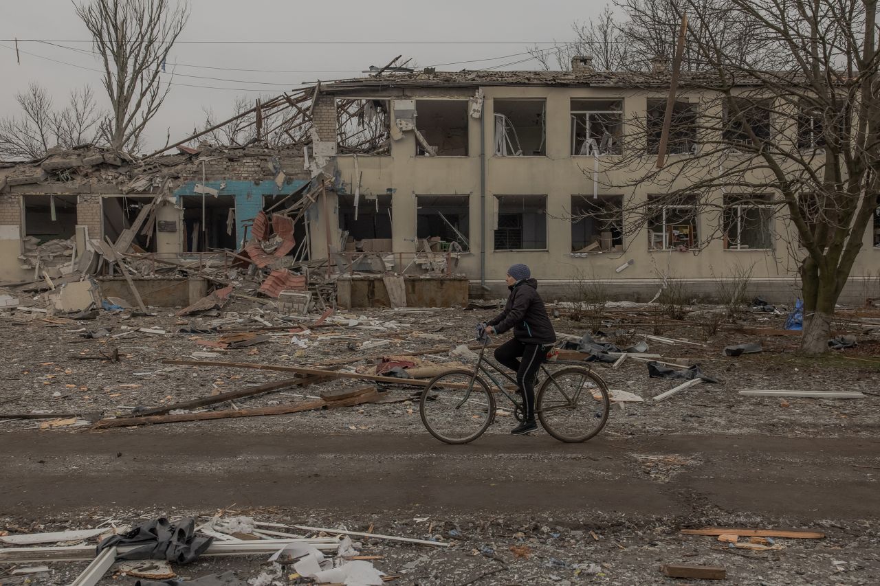 A woman rides a bicycle past a destroyed school building following a recent shelling in the village of Novopavlivka, Dnipropetrovsk region, on January 30, 2025, amid the Russian invasion of Ukraine. (Photo by Roman PILIPEY / AFP) (Photo by ROMAN PILIPEY/AFP via Getty Images)