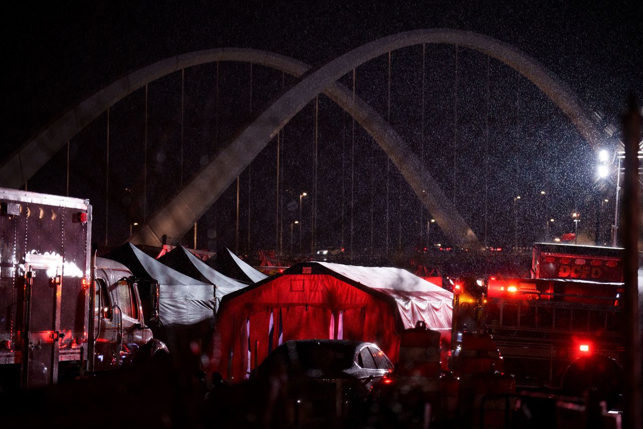 The Frederick Douglass Memorial Bridge is visible as the service members' bodies depart Buzzard Point in Washington, DC.