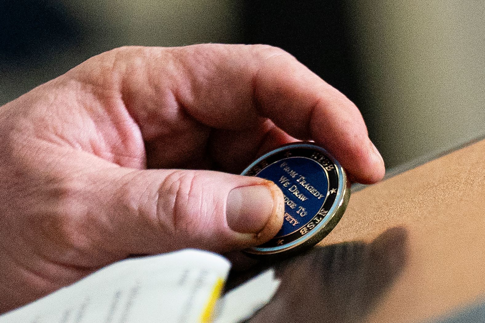 J. Todd Inman, a member of the National Transportation Safety Board, holds a challenge coin during a news conference at Reagan National Airport on Saturday, February 1. The coin reads, “From tragedy we draw knowledge to improve safety for us all."