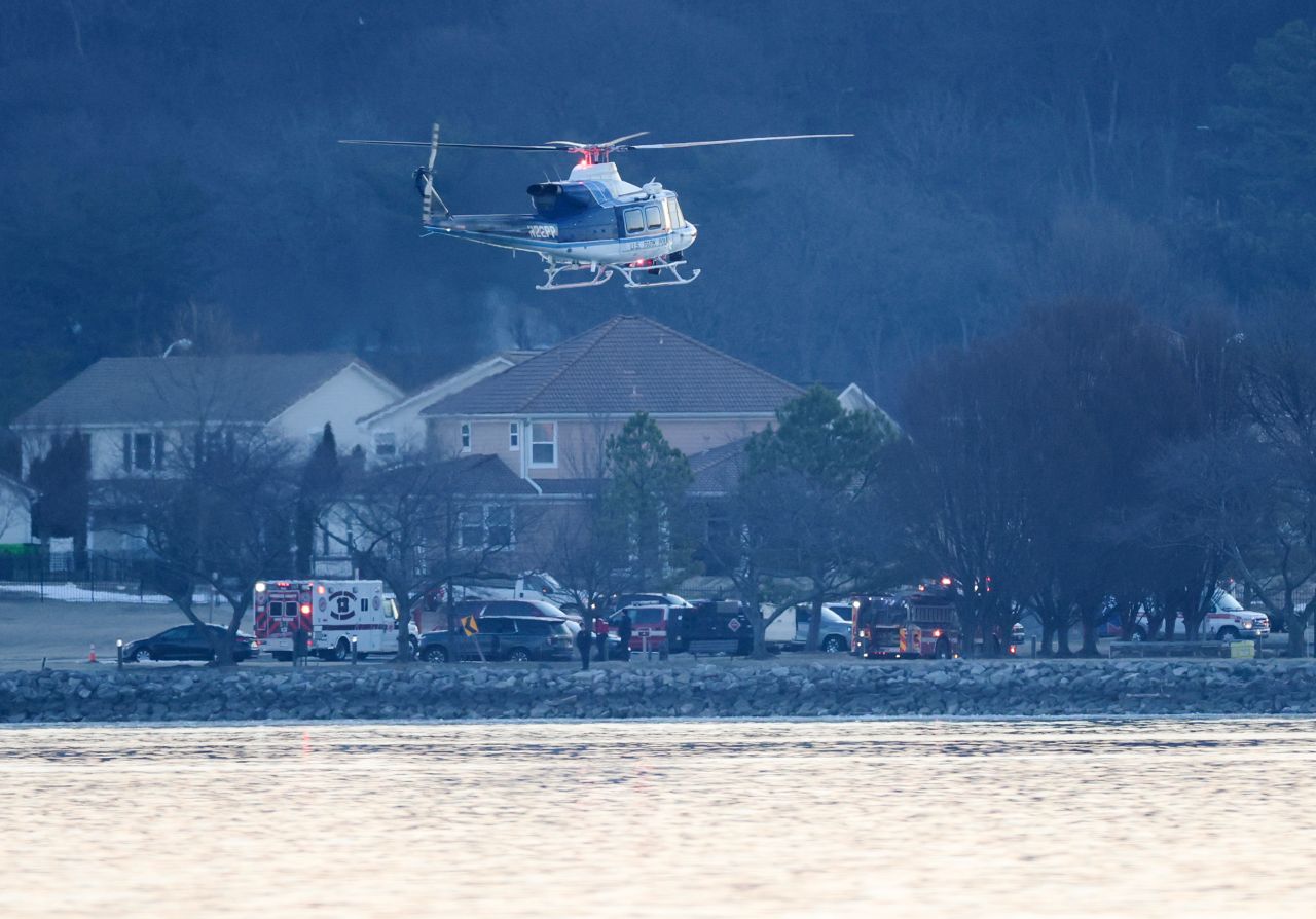 A helicopter flies near other first responders as they work the crash site Thursday in Arlington, Virginia.